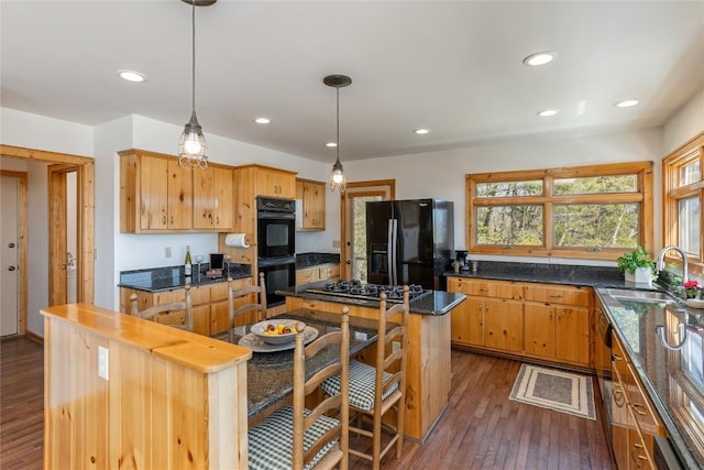 kitchen featuring recessed lighting, dark wood-style flooring, a sink, black appliances, and a center island