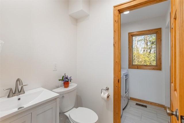 bathroom with visible vents, washer / dryer, toilet, and vanity