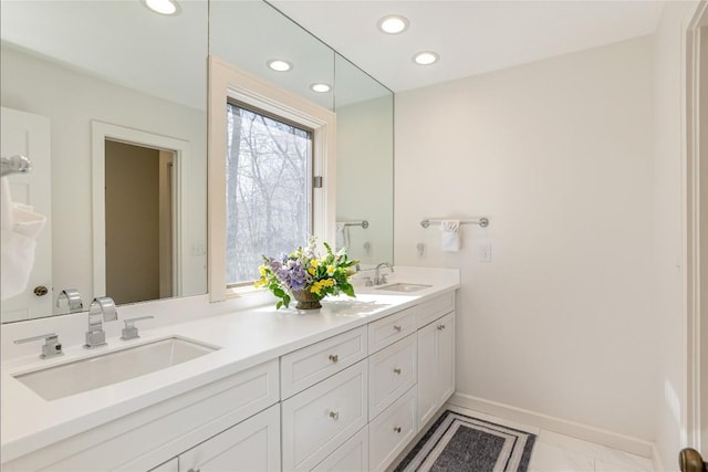 bathroom featuring double vanity, recessed lighting, baseboards, and a sink