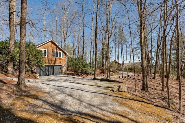 view of yard with an attached garage and gravel driveway