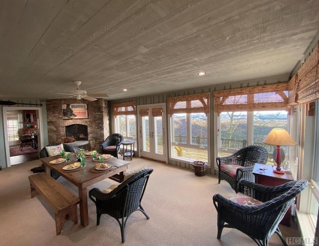 sunroom featuring a stone fireplace and ceiling fan