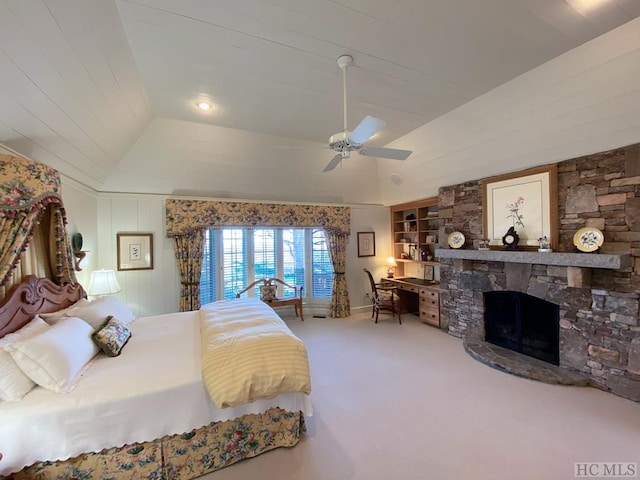 bedroom with lofted ceiling, a stone fireplace, carpet, and ceiling fan