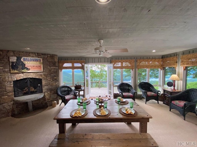 sunroom / solarium featuring a stone fireplace and ceiling fan