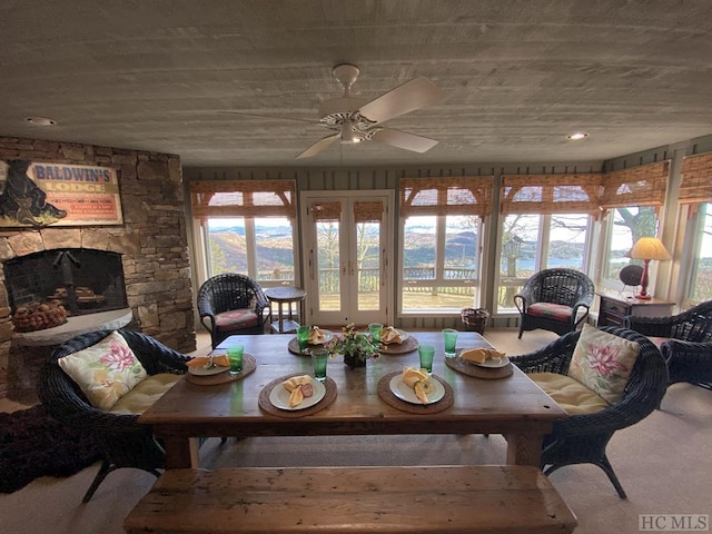 dining area featuring ceiling fan, a stone fireplace, and carpet