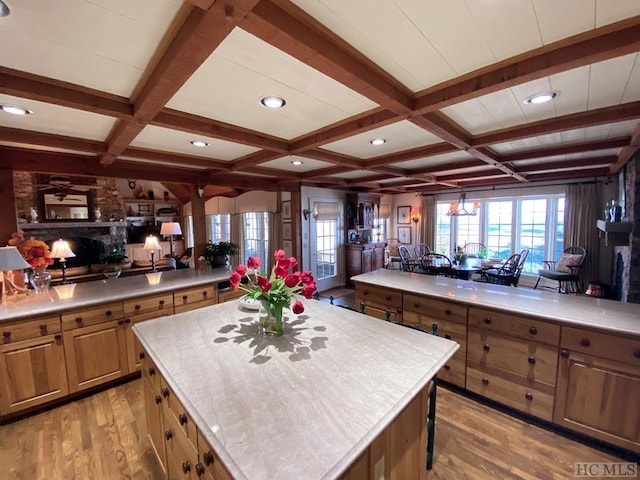 kitchen featuring a large island, a fireplace, coffered ceiling, and light wood-type flooring