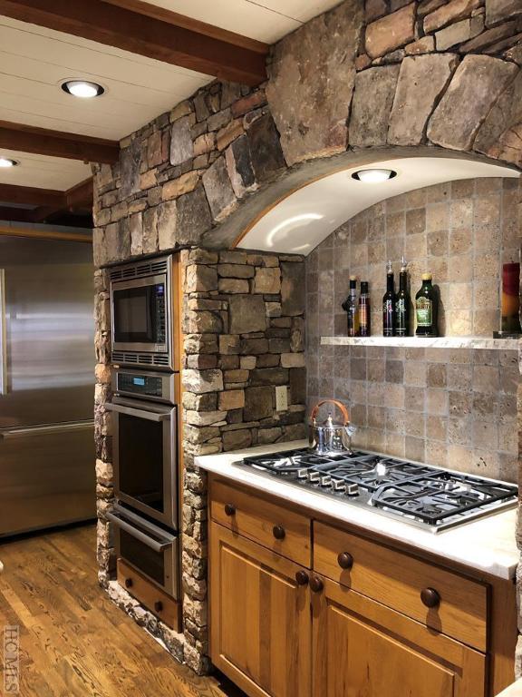 kitchen featuring beamed ceiling, built in appliances, and dark wood-type flooring