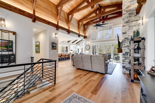 living room featuring high vaulted ceiling, wood ceiling, a ceiling fan, light wood-type flooring, and beam ceiling