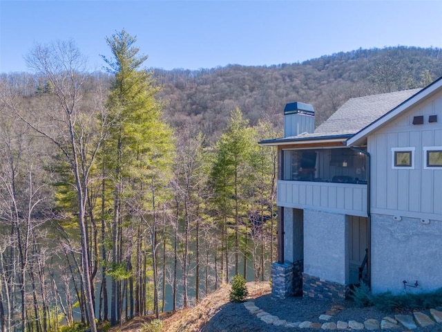 1132 Southshore Dr, Tuckasegee, NC 28783 - view of side of home featuring roof with shingles, a chimney, board and batten siding, a sunroom, and a view of trees