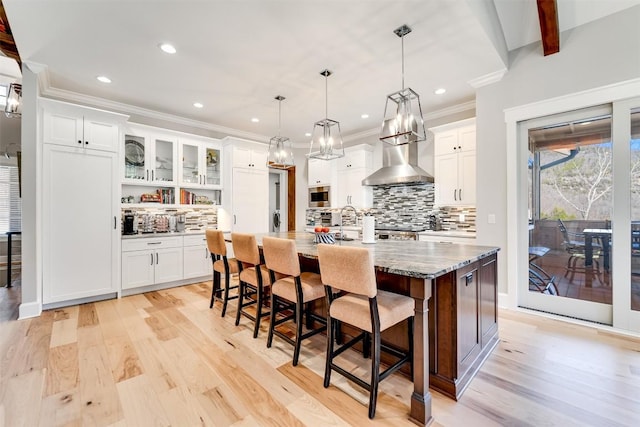 1132 Southshore Dr, Tuckasegee, NC 28783 - kitchen featuring light wood-type flooring, white cabinets, wall chimney range hood, and a breakfast bar area