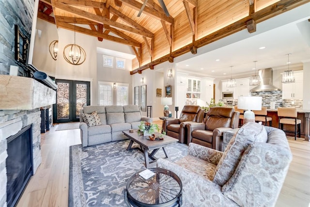 1132 Southshore Dr, Tuckasegee, NC 28783 - living room featuring light wood-style flooring, a fireplace, french doors, beamed ceiling, and an inviting chandelier