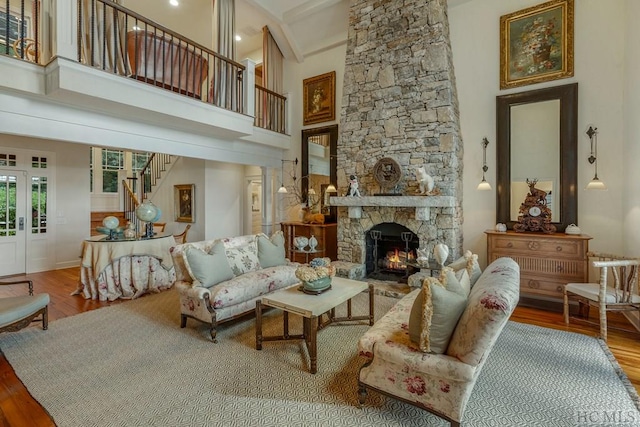 living room featuring a fireplace, hardwood / wood-style floors, a towering ceiling, and french doors