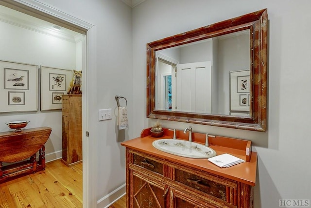 bathroom featuring crown molding, wood-type flooring, and vanity