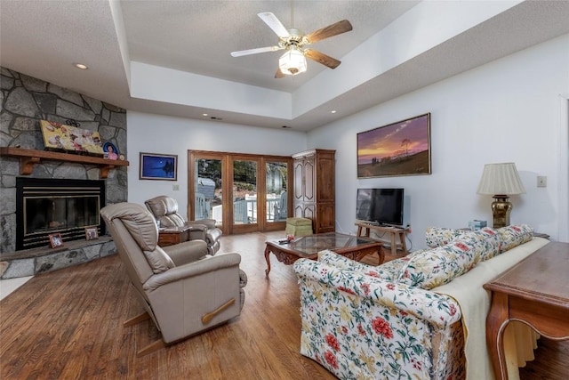 living room featuring light wood-style flooring, a fireplace, ceiling fan, and french doors