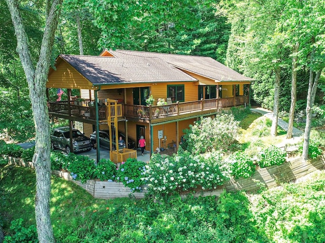 back of house with a patio, a forest view, a shingled roof, and a wooden deck