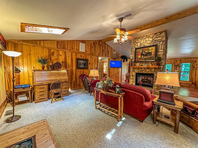living area featuring a stone fireplace, vaulted ceiling with beams, wood walls, and ceiling fan