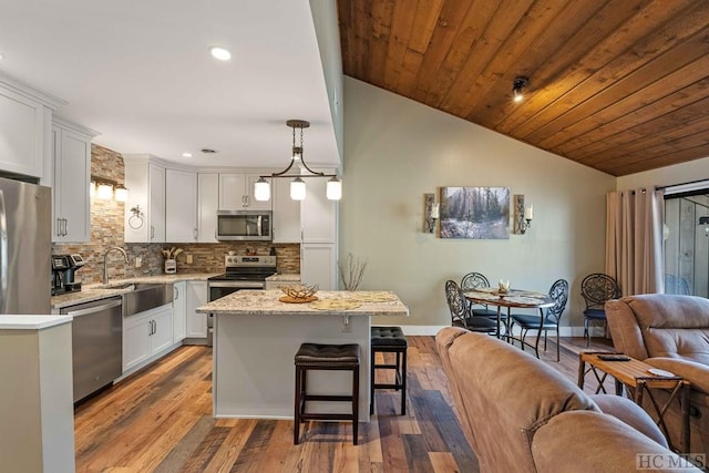 kitchen with sink, tasteful backsplash, decorative light fixtures, a center island, and stainless steel appliances