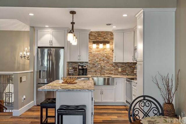 kitchen featuring decorative light fixtures, tasteful backsplash, sink, white cabinets, and stainless steel appliances