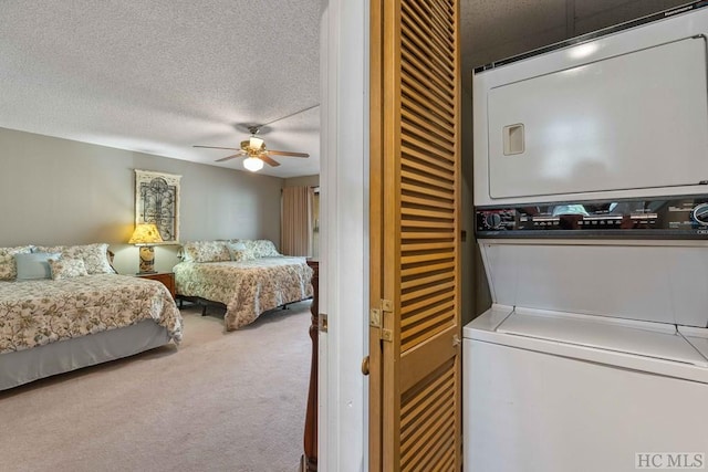 carpeted bedroom featuring stacked washer and clothes dryer, a textured ceiling, and ceiling fan