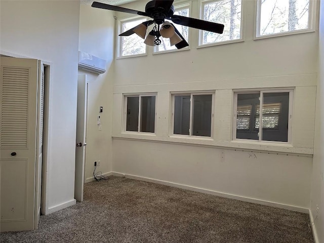 interior space with dark carpet, an AC wall unit, ceiling fan, and a high ceiling