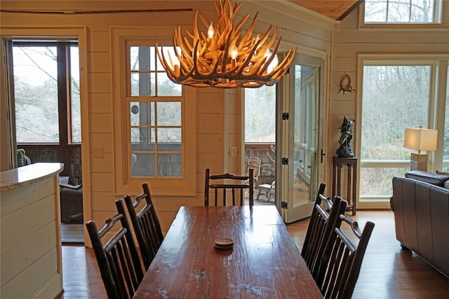 dining area with a notable chandelier, wood walls, lofted ceiling, and wood finished floors