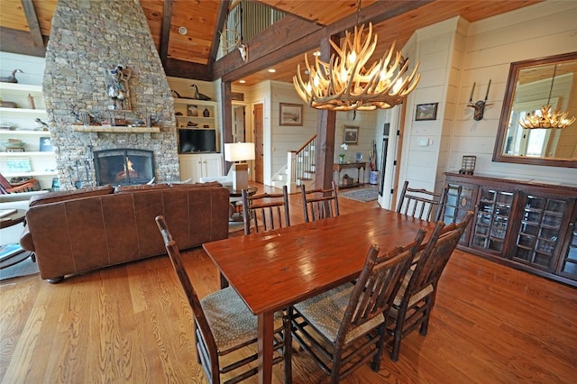 dining area featuring a chandelier, wood finished floors, stairway, built in shelves, and wood walls