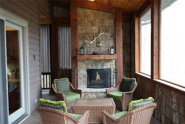 sunroom with wooden ceiling and an outdoor stone fireplace