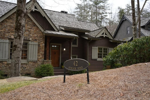 view of exterior entry with crawl space, metal roof, stone siding, and a standing seam roof