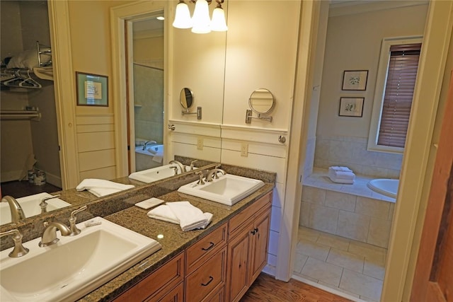 bathroom featuring double vanity, tiled tub, and crown molding