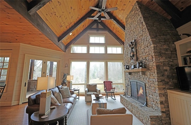 living area with wooden ceiling, a stone fireplace, beam ceiling, high vaulted ceiling, and ceiling fan
