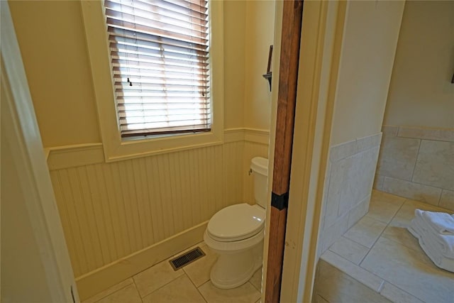 bathroom featuring a wainscoted wall, toilet, and tile patterned flooring