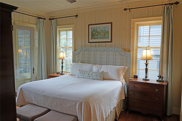 bedroom with wooden walls, multiple windows, and ornamental molding