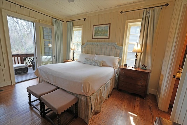 bedroom with ornamental molding, access to exterior, wood finished floors, multiple windows, and wood walls