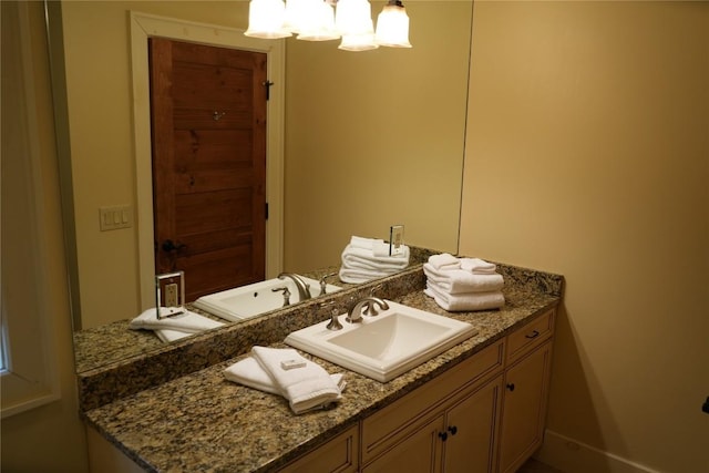 bathroom with a notable chandelier, vanity, and baseboards