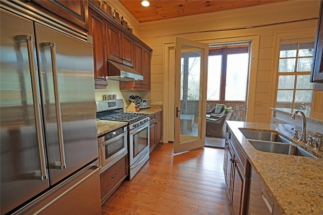 kitchen with stainless steel appliances, a sink, under cabinet range hood, french doors, and light wood-style floors