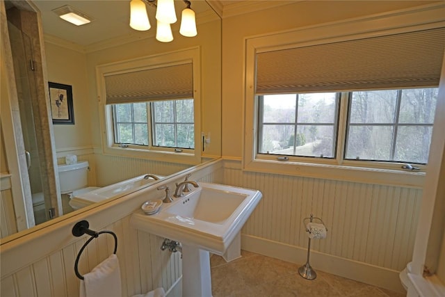 bathroom with ornamental molding, wainscoting, tile patterned flooring, a chandelier, and a decorative wall
