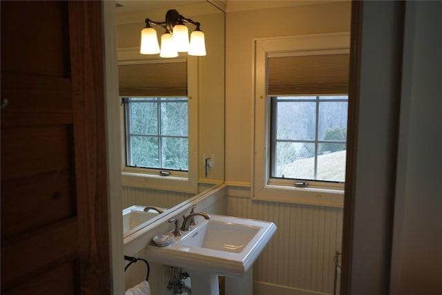 bathroom with a healthy amount of sunlight, a wainscoted wall, and a sink