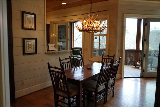 dining space with recessed lighting, a chandelier, wood walls, and dark wood-style flooring