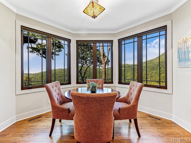 dining area with hardwood / wood-style flooring and ornamental molding