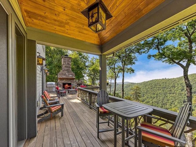 wooden deck with a mountain view and an outdoor stone fireplace