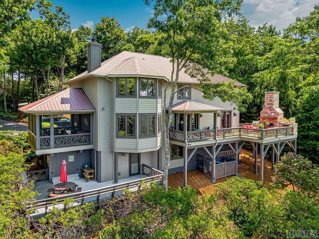 back of property featuring a gazebo, a sunroom, and a fireplace