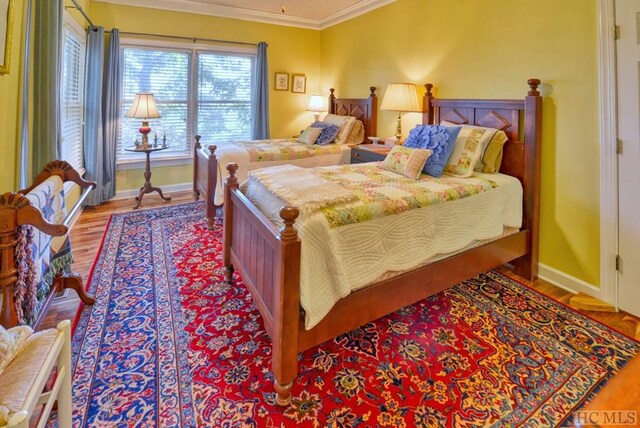 bedroom featuring crown molding and light hardwood / wood-style flooring