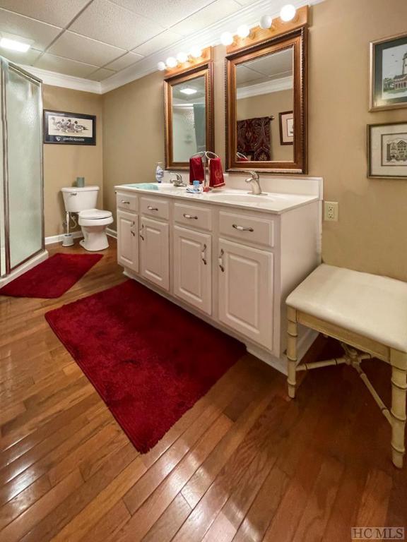 bathroom with crown molding, vanity, wood-type flooring, toilet, and walk in shower