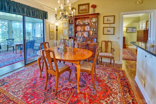 dining space with ornamental molding, a chandelier, and light wood-type flooring