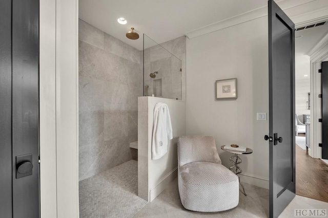 bathroom with tile patterned flooring, crown molding, and a tile shower