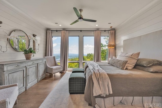 bedroom featuring wood-type flooring, ceiling fan, and wood walls