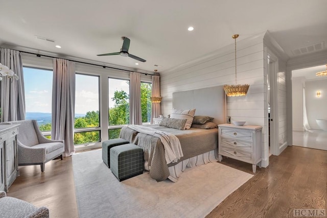 bedroom featuring hardwood / wood-style flooring, ceiling fan with notable chandelier, and wood walls