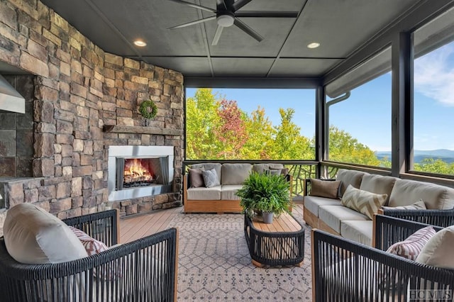 sunroom / solarium featuring ceiling fan and an outdoor stone fireplace