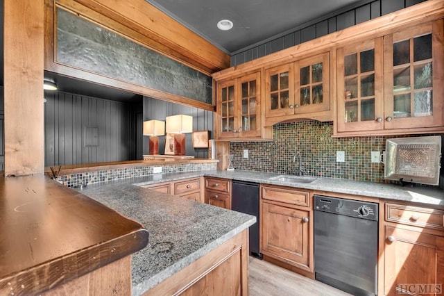 kitchen with stone countertops, tasteful backsplash, dishwasher, sink, and light wood-type flooring