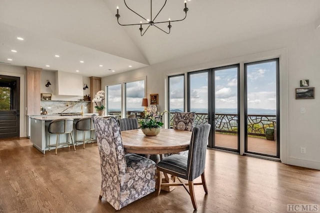 dining area with an inviting chandelier, high vaulted ceiling, and light wood-type flooring