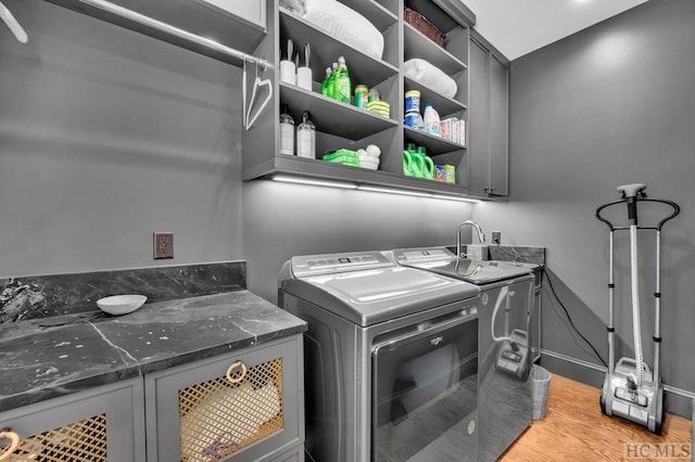 laundry room with washer and dryer, light hardwood / wood-style flooring, and cabinets